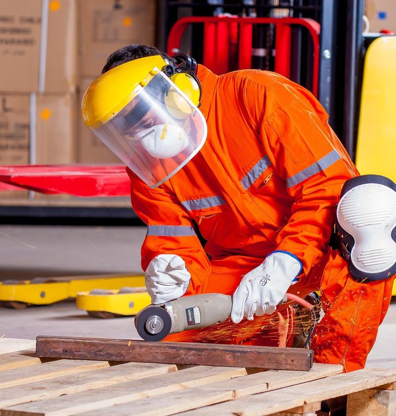 Worker in orange coveralls using an angle grinder